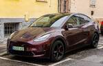 Hier ist ein Telsa Model Y in der Farbe Midnight Cherry beim regnerischen Wetter zu sehen.