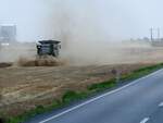 CLAAS LEXION-750 wirbelt nächst Dragaline(Rumänien) bei der Weizenernte, bzw. beim Spreuauswurf mächtig Staub auf, die Siloanlagen im Hintergrund wartem sicher schon auf die mehlhaltigen Körner; 230706