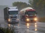 MAN mit Planenauflieger am 19.10.2010 im strömenden Regen auf der A4 bei Aachen Richtung Niederländische Grenze unterwegs. Der Fahrer im Scania  Silozug auf der linken Spur riskiert gerade 80 Euro und einen Punkt für Überholen im LKW Überholverbot.