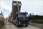 Volvo Kipperlkw liefert Asphalt an, um den Graben von einer Straßenbaustelle aufzufüllen und somit die Straße wieder befahrbar zu machen.