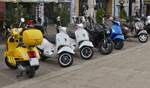 Verschiedene Vespa Motorroller, dazwischen eine Kawasaki Maschine, gesehen auf einem Parkplatz f�r Motorr�der.
