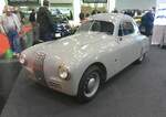 Fiat 1100  Gobbone  aus dem Jahr 1949. Dieses Fiat Modell wurde unmittelbar nach dem Ende von WW2 unter der Leitung des legendären Dante Giacosa (*1905 +1966) konzipiert. Mit diesem Modell nahm Fiat an der nun wieder aufgelebten  Mille Miglia  teil. Auf der technischen Grundlage des Vorkriegsmodells 508C versah er das Auto mit einer zweckmäßigen, aerodynamischen, Karosserie aus Aluminium. Das Auto wurde tiefer gelegt und war frei von überflüssigem Zierrat. Der Spitzname  Gobbone , zu deutsch der Bucklige, bezieht sich auf das markant geschwungene Heckprofil des Wagens. Sein dreiteiliger Kühlergrill mit horizontalen Streben, die eine vertikale Mitte flankieren, wurde zu einem optischen Markenzeichen dieses Modells. Die technischen Daten sind folgende: Vierzylinderreihenmotor mit einem Hubraum von 1089 cm³ und einer Leistung von 51 PS. Bei einem Leergewicht von 825 Kilogramm reicht diese Motorleistung für eine Spitzengeschwindigkeit von 150 km/h. Während die meisten 1100´er-Modelle im Heimatland und in die Nachbarländer ausgeliefert wurden, wurde das gezeigte Auto als Neuwagen nach Caracas/Venezuela ausgeliefert. Retro Classics in Essen am 09.04.2026.