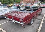 Heckansicht eines Ford Mustang 1 Convertible im Farbton vintage burgundy aus dem ersten Modelljahr 1964. 