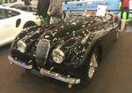 Jaguar XK120 DHC (D rop H ead C oupe) aus dem Jahr 1954 im Farbton black. Auf der London Motor Show des Jahres 1948 stellte Jaguar mit der Baureihe XK120 den Nachfolger der legendären Baureihe SS100 vor. Zuerst war das Modell als recht spartanisch ausgestatteter XK120 OTS (O pen T wo S eater) lieferbar. Ab 1953 war zusätzlich eine geschlossene Coupe-Version namens FHC (F ixed H ead Coupe) lieferbar. Das XK120 DHC ergänzte nur im Jahr 1953 und 1954 die XK120 Modellpalette. Das Modell war etwas luxuriöser ausgestattet und hatte dann auch ein gefüttertes Cabriolet-Verdeck. Das Modell verkaufte sich bis zum Produktionsende der XK120-Baureihe genau 1767 mal. Der Sechszylinderreihenmotor hat einen Hubraum von 3442 cm³ und leistet in diesem Fahrzeug 160 PS. 