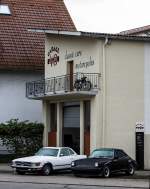 Porsche 911 (G-Modell) und Mercedes-Benz Mercedes SL Roadster (R107) parkieren vor dem Garage48 in Hockenheim.