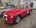 MG B GT 1800. Der MG B Roadster wurde bereits 1962 eingeführt. Im Oktober 1965 kam der als 2+2 Sitzer ausgelegte MG B GT zusätzlich auf den Markt. Er war, genau wie der Roadster, bis 1980 im Verkaufsprogramm der Marke aus Coventry. Während sich das Roadster Modell während der gesamten Produktionszeit fast 400.000 mal verkaufte, wurde vom GT Modell genau 125.282 Einheiten abgesetzt. Der Vierzylinderreihenmotor hat einen Hubraum von 1798 und leistet 92 PS. Die Höchstgeschwindigkeit lag bei 168 km/h. Der gezeigte Wagen wurde im Jahr 1978 produziert und dürfte im Farbton flamenco red lackiert sein. Außengelände der NEC Birmingham im Juli 2024.