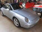 Porsche 911 Targa der Baureihe 993 im Farbton polarsilber. Der 993 wurde anfänglich als  Carrera  mit Heckantrieb und als  Carrera 4 , wie die $ schon erkennen lässt, mit Allradantrieb gebaut. Den kurze Zeit später vorgestellten Targa (Foto) gab es nur mit Heckantrieb. Serienmäßig hat der im Heck verbaute, Gebläse-gekühlte, Sechszylinderboxermotor einen Hubraum von 3600 cm³ und leistet 272 PS. Die Höchstgeschwindigkeit gab das Werk in Zuffenhausen mit 270 km/h an. War das Automaticgetriebe  Tiptronic  verbaute, verringerte sich diese um 5 km/h. Classic Remise Düsseldorf am 15.01.2026.