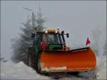Deutz Traktor mit Schneeschieber und Salzstreuer ist damit beschftigt enge Strassen vom Schnee zu befreien und zu streuen.