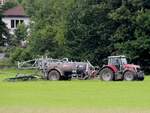 MF bringt mit dem Vakutec-Güllefass Jauche auf die Wiesen nächst einer Wohnsiedlung; 250731