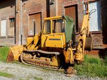 JOHN-DEERE Raupe mit Heckbagger, vor historischem Backsteinbau; 150508