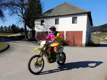 SUZUKI-Motocrossmaschine auf einem asphaltierten Güterweg im hügeligen Mühlviertel; 150318