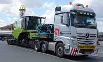 MB Actros 2745 transportiert einen Claas-Mähdrescher von Typ Avero 240. Gesehen auf dem Autohof Werneck im Juli 2015.