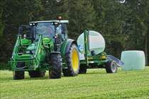 Nach dem Pressen der Heuballen werden sie mit einer Wickelmaschine der Marke McHale mit Folie Luftdicht verpackt.  
Gezogen wird die Maschine von einem John Deere Traktor. Mai 2019
