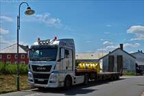 MAN Sattelzug mit einer Landmaschine beladen hält kurz am Straßenrand. Juni 2019