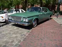 Chrysler Newport fourdoor Sedan des Modelljahres 1963. Von diesem Modell verkaufte Chrysler im Jahr 1963 49.067 Einheiten. Angetrieben wird der, im Farbton teal green lackierte Newport, von einem V8-Motor mit einem Hubraum von 5907 cm³. Die Leistung beträgt 265 PS. Wurde anstatt der serienmäßigen Doppelvergaseranlage eine aufpreispflichtige Vierfachvergaseranlage bestellt, steigerte sich die Motorleistung auf 340 PS. Oldtimertreffen Meldorf im Mai 2018.