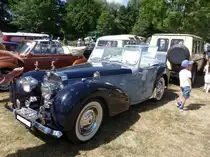 Triumph 1800 Roadster, gebaut in den Jahren von 1946 bis 1948. Mit diesem Roadster-Modell nahm die Firma aus Coventry im Jahr 1946 wieder den Bau von Autos auf. Das Modell war schon zu Beginn von WW2 konstruiert worden. Eine pfiffige Lösung war die Konstruktion der aufklappbaren Windschutzscheiben für die Passagiere auf den hinteren beiden Notsitzen. Das Fahrzeug war schwer und unhandlich und verkaufte sich lediglich 4500 mal. Der Vierzylinderreihenmotor hat einen Hubraum von 1776 cm³ und leistet 50 PS. Mittels eines Vierganggetriebes, teilweise mit Overdrive, erreichte der 1800 Roadster immerhin eine Höchstgeschwindigkeit von 130 km/h. Oldtimertreffen in Melderslo/NL zu Pfingsten 2017.