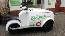Seitenansicht eines dreirädrigen Motorrollers mit Lastenbox vorne als Transporter für Obstkörbe. Aufgenommen am 08.06.2020 in Berlin.