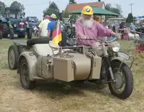 =BMW Wehrmachtsgespann mit Ahänger rollt bei der Oldtimerausstellung in Uttrichshausen über das Ausstellungsgelände. Der Fahrer präsentiert eine zeitgenössische Helmvariante in wehrmachtsuntauglichem Gelbton, 07-2019