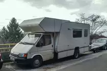 Jemand hat von einem Ford Transit einen Wohnwagen gebastelt und noch einen Autotrasporter am Ende angehängt. Aufnahme: Januar, 2020.