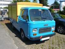 Fiat 900E mit einem Pritschenaufbau der Carrozzeria Coriasco/Turin. Der Kleintransporter 900E kam 1979, als Weiterentwicklung des bereits im Jahr 1970 erschienenen Fiat 850T auf den Markt. Angetrieben wurde dieser Lieferwagen vom, im Heck verbauten, Motor des Fiat 127. Dieser Motor hat einen Hubraum von 903 cm³ und leistet 35 PS. Die Höchstgeschwindigkeit gab das Werk mit 100 km/h an. An dem roten Streifen auf der vorderen Stoßstange kann man erkennen, dass dieser Fiat früher in Italien unterwegs war. Der rote Streifen bedeutet, dass mit dem Auto nur Produkte der eigenen Firma transportiert wurden. Mülheim an der Ruhr Saarn am 25.07.2021.