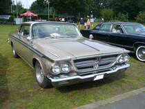 Chrysler 300 Hardtop Coupe aus dem Modelljahr 1964 im Farbton regal gold. Die in allen Karosserieversionen lieferbare Baureihe 300-K war in diesem Modelljahr das Spitzenmodell in der Chrysler-Produktpalette. Darunter rangierten die Baureihen New Yorker und als Basismodell der Newport. Das Modell konnte nur mit einem V8-Motor mit einem Hubraum von 413 cui (6768 cm³) mit einer Leistung von 360 PS oder 390 PS bestellt werden. Oldtimertreffen an der Dreieckswiese in Duisburg am 01.08.2021.