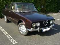 Alfa Romeo 2000 Berlina, gebaut von 1971 bis 1976. Grundsätzlich basierte die Berlina 2000 und ihr kleineres Schwestermodell 1750 auf der paralell produzierten Giulia. Der Radstand wurde um ca. 7 cm verlängert, um die Modelle exclusiver aussehen zu lassen. Der Vierzylinderreihenmotor leistet 133 PS aus einem Hubraum von 1962 cm³. Die Höchstgeschwindigkeit gaben die Milanesen mit 185 km/h an. Besucherparkplatz der Düsseldorfer Classic Remise am 15.08.2021.