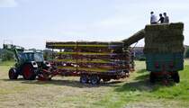 Heuernte mit dem Quaderballensammelwagen der Firma Kemper, der zapfwellenbetriebene Ladewagen nimmt während der Fahrt die Ballen auf und transportiert sie auf der Karussell ähnlichen Vorrichtung bis in die oberste Etage, wo sie anschließend entladen werden können, Juli 2021