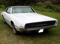 Ford Thunderbird twodoor aus dem Modelljahr 1967 im Farbton wimbledon white. Im Jahr 1967 kam die fünfte Serie des  Thunderbird  auf den Markt. Aufgrund der großen Karosserien und den technischen Finessen, sprach man hier auch von den  Glamour-Thunderbirds . So waren z.B. die vorderen Scheinwerfer vom Kühlergrill verdeckt. Erstmals war 1967 auch ein viertüriger  Donnervogel  lieferbar. Fast 53.000 zweitürige Coupe´s und fast 25.000 viertürige Limousinen setzte Ford im Modelljahr 1967 vom T-Bird ab. Der Basispreis eines solchen Coupes lag bei US$ 4603,00. Der V8-Motor hat einen Hubraum von 6384 cm³ und leistet wahlweise 270 PS oder 315 PS. Classic Festival auf Schloss Lembeck im Juli 2019.