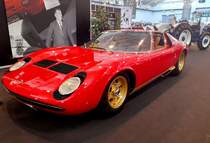 Lamborghini P400S Miura, gebaut von 1968 bis 1971. Der Lamborghini P400 Miura wurde im März 1966 auf dem Genfer Automobilsalon vergestellt. Der Sportwagen entstand durch die Zusammenarbeit von Bertone und Ferrucio Lamborghini. Bei seiner Präsentation im Herbst 1966 übertrafen die Vorbestellungen alle Erwartungen der Werksleitung. Während die Straßenlage begeisterte, stieß bei einigen Miura-Besitzern die Verarbeitungsqualität auf Kritik. 1968 ergänzte der gezeigte P400S die Modellpalette nach oben. Das 140 mal produzierte P400S-Modell hat einen, als Mittelmotor verbauten, V12-Motor. Dieser Motor hat einen Hubraum von 3929 cm³ und leistet 370 PS. Die Höchstgeschwindigkeit wurde vom Werk mit 280 km/h angegeben. Techno Classica Essen am 27.03.2022.