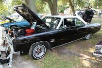 Profilansicht eines 1965´er Plymouth Sport Fury III Hardtop Coupe im Farbton ebony. Das Modell Sport Fury gab es im Modelljahr 1965 nur als zweitüriges Cabriolet und als zweitüriges Hardtop Coupé. Basisimotorisierung war ein Sechszylinderreihenmotor mit einem Hubraum von 3682 cm³ und einer Leistung von 145 PS. Diese Motorisierung wurde aber kaum gewählt. Die meisten Kunden entschieden sich für einen, der drei im Jahr 1965 lieferbaren, V8-Motoren. Es gab folgende Größen: 5210 cm³ mit 230 PS, 6286 cm³ mit 290 PS oder 330 PS und 6974 cm³ mit einer Leistung von ca. 360 PS. Oldtimertreffen der Magnolia Classic Cruiser in Pascagoula/Jackson County/Mississippi im September 2021.