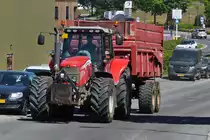 Massey Ferguson mit großem Hänger ist auf dem Weg zu einem Feld um Silageschnittgut abzuholen. 06.2022