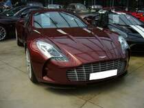 Aston Martin One-77 aus dem Jahr 2011. Wie die Typenbezeichnung es teilweise schon verrät. Von 2009 bis ins Jahr 2011 wurden genau 77 Sportwagen dieses Typs in Handarbeit hergestellt. Angeblich sollen in jedes der 77 hergestellten Fahrzeuge mindestens 2700 Arbeitsstunden geflossen sein. Der von Cosworth verfeinerte V12-Motor hat einen Hubraum von 7312 cm³ und leistet 760 PS. Die Höchstgeschwindigkeit gab das Werk mit 355 km/h an. Ein solcher One-77 kostete in seinem Heimatland 1.250.000,00 Pound Sterling zuzüglich Steuern. Classic Remise Düsseldorf am 12.07.2022.