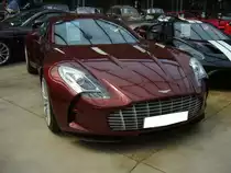 Aston Martin One-77 aus dem Jahr 2011. Wie die Typenbezeichnung es teilweise schon verrät. Von 2009 bis ins Jahr 2011 wurden genau 77 Sportwagen dieses Typs in Handarbeit hergestellt. Angeblich sollen in jedes der 77 hergestellten Fahrzeuge mindestens 2700 Arbeitsstunden geflossen sein. Der von Cosworth verfeinerte V12-Motor hat einen Hubraum von 7312 cm³ und leistet 760 PS. Die Höchstgeschwindigkeit gab das Werk mit 355 km/h an. Ein solcher One-77 kostete in seinem Heimatland 1.250.000,00 Pound Sterling zuzüglich Steuern. Classic Remise Düsseldorf am 12.07.2022.