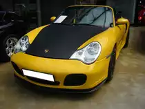 Porsche 911 Cabriolet der Baureihe 996 im Farbton speedgelb. Der gezeigte Porsche der Baureihe 996 wurde im Oktober 2003 ausgeliefert. Die Ausstattung hatte es in sich: Carbonpaket, Keramikbremsen, das X50-Leistungssteigerungspaket, sowie gelbe Nähte (passend zur Außenlackierung) an den Ledersitzen. Der im Heck verbaute, wassergekühlte, Sechszylinderboxermotor hat einen Hubraum von 3596 cm³ und leistet, aufgrund des X50-Paketes, 450 PS. Classic Remise Düsseldorf am 12.07.2022.