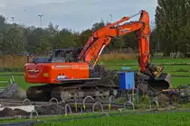 Raupenbagger ZAXIS 210 LC, steht an einer Baugrube auf einer Wiese. 11.2022 