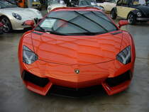 Frontansicht eines Lamborghini Aventador LP700-4 Coupe. Der Aventador wird seit dem Jahr 2011 produziert. Der, im Farbton arancio atlas lackierte, Sportwagen wird von einem, als Mittelmotor verbauten, V12-Motor angetrieben. Der Motor hat einen Hubraum von 6498 cm³ und leistet 700 PS. Classic Remise Düsseldorf am 30.12.2022.