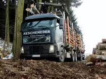 VOLVO FH12-460 samt Hänger wird auf unwegsamen Waldweg mit Fichtenstämmen beladen; 140130