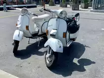 Zwei weisse Vespas die am 17.6.23 beim Bahnhof Spiez parkiert sind.