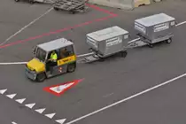 Kleiner Schlepper unterwegs mit 2 Koffercontainer auf dem Flughafen von Wien. 06.2023