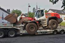 Caterpillar 566 Radlader steht auf einem Schwerlasthänger, aufgenommen nahe einer Bahnbaustelle in Enscherange. 25.08.2023