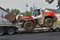 Caterpillar 566 Radlader steht auf einem Schwerlasthänger, aufgenommen nahe einer Bahnbaustelle in Enscherange. 25.08.2023