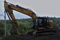 Caterpillar Raupenbagger wartet an der Schotterverladestelle, an der Bahnbaustelle nahe Drauffelt, auf den nächsten LKW zum beladen mit dem alten Schotter. 08.2023

