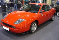 Fiat Coupe 2000 aus dem Jahr 1998. Als das Modell im Jahr 1994 auf den Markt kam, gab es nichts vergleichbares und umso polarisierender war das Design. Das Außendesign wurde vom US-amerikanischen Designer Chris Bangle (*1956) gezeichnet und im Innenraum setzte sich ein Entwurf von Pininfarina durch. Dieses Fiat Coupé wurde am 31.3.1998 im österreichischen Villach an eine ältere Dame ausgeliefert, die den Wagen selten genutzt und pfleglich behandelt hat. So sind in den bisherigen 25 Jahren nur 57.152 Kilometer zusammen gekommen. Angetrieben wird das extravagante Auto von einem Fünfzylinderreihenmotor mit einem Hubraum von 1998 cm³ und einer Leistung von 147 PS. Essen Motorshow am 06.12.2023.