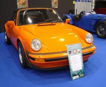 Porsche 911 SC Cabriolet aus dem Jahr 1983. Mit dem Modelljahr 1978 hatten die  Zuffenhausener  den Carrera aus dem Programm gestrichen. Das neue Modell SC hielt, abgesehen vom Turbo alleine die Fahne des Porsche 911 hoch. Der 911 SC hatte die breitere Karosserie des 911 Carrera. Die Zusatzbezeichnung SC sollte an den Porsche 356 SC erinnern. Die Zusatzbezeichnung bedeutet angeblich  S uper C arrera . Der im Heck verbaute, gebläsegekühlte Sechszylinderboxermotor hat einen Hubraum von 2956 cm³ und leistet 207 PS. Die Höchstgeschwindigkeit wurde mit 235 km/h angegeben. Essen Motorshow am 06.12.2023.