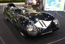 Lotus Eleven aus dem Jahr 1956. Der Wagen trug ursprünglich die Typenbezeichnung  Mark 11 , wurde aber von der Motorpresse schnell als Lotus Eleven bezeichnet. Lotus übernahm dann diese Typenbezeichnung. Frühe Lotus-Fahrzeuge trugen ihre Mark-Typennummern teilweise auch in römischen Zahlen, so das die  11  auch als  II  gelesen werden konnte. Um Verwirrungen zu vermeiden, wurde beschlossen, es zu buchstabieren. So wurde das Auto zum Lotus  Eleven  und führte somit unbeabsichtigt die  E-Namenspolitik  für alle nachfolgenden Lotus-Straßenfahrzeuge ein. Lotus-Gründer Colin Chapman (*1928 +1982) selbst nahm mit einem solchen  Eleven  an den 24 Stunden von LeMans in der 1500 cm³-Klasse teil, musste aber aufgeben. Der Vierzylinderreihenmotor aus dem Hause Coventry-Climax hat einen Hubraum von 1460 cm³ und leistet 149 PS. Essen Motorshow am 06.12.2023.