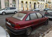 Rückansicht / Seitenansicht: Opel Astra F Stufenheck in rot. Foto: Dezember, 2022.