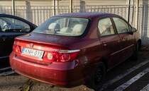 Rückansicht / Seitenansicht: Honda City (auf dfem Basis des Honda Jazz Mk1) in der Farbe Tange Red, gesehen in Januar, 2023.