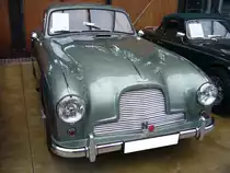 Aston Martin DB2/4 MK I Saloon aus dem Jahr 1955 im Originalfarbton seagreen. Produziert wurde das Modell in den Jahren von 1953 bis 1955. Hier wird einer der letzten Wagen dieser Baureihe gezeigt, der im Mai 1955 erstmalig in der englischen Gemeinde Martons zugelassen wurde. Er ist mit einem Sechszylinderreihenmotor ausgerüstet, der aus einem Hubraum von 2922 cm³ serienmäßig 142 PS leistet. Durch einige technische Verbesserungen leistet dieses Auto allerdings 180 PS und kann den Wagen, je nach gewählter Getriebeübersetzung, auf bis zu 225 km/h beschleunigen. Classic Remise Düsseldorf am 26.02.2024.