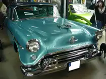Oldsmobile 88 fourdoor Sedan aus dem Jahr 1954. Im Modelljahr 1954 war die Baureihe 88 das Basismodell in der Produktpalette der GM-Tochter Oldsmobile. Darüber waren die Modellreihen Super 88 und 98 angesiedelt. Den 88 gab es in drei Karosserieversionen, nämlich den zweitürigen Sedan, den viertürigen Sedan (Foto) und das ebenfalls zweitürige Holiday Hardtop Coupe. Von der Karosserieversion fourdoor Sedan wurden im Modelljahr 1954 29.028 Fahrzeuge zu einem Preis ab US$ 2126,00 verkauft. Der so genannte  Rocket  V8-Motor hat einen Hubraum von 5307 cm³ und leistet 170 PS. Oldtimertreffen beim Autohaus Voss in Rosendahl-Darfeld am 07.04.2024.