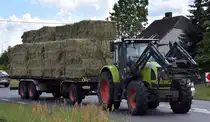 Ein CLAAS Traktor Typ Ares mit Hänger mit Heuballen am 12.06.24 Bahnübergang Bahnhof Rodleben.